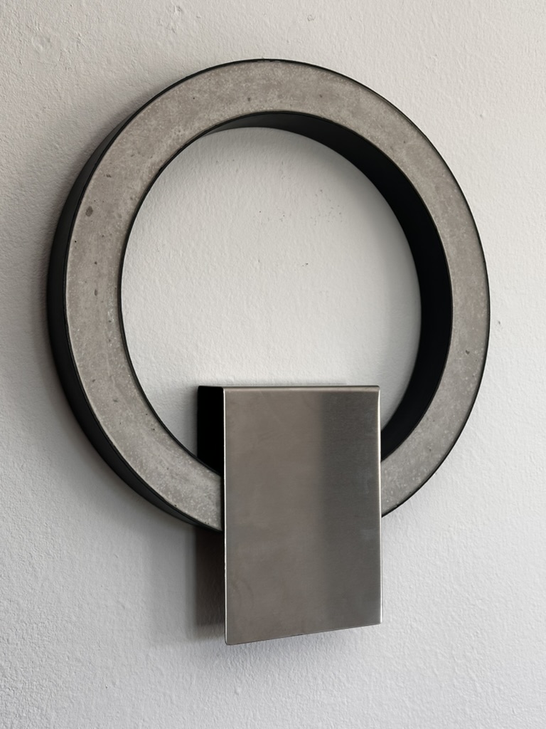 Wall sculpture of concrete ring and brushed metal plate